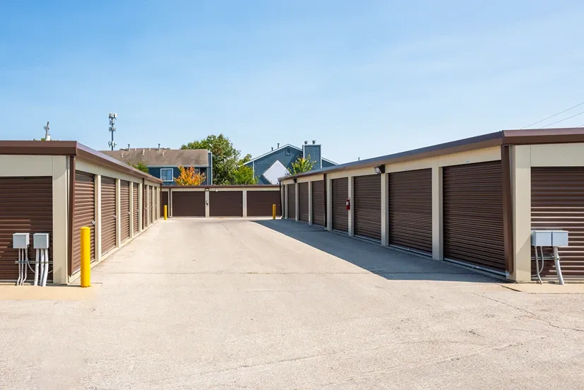 Drive-up storage units with brown roll-up doors and wide concrete access lane