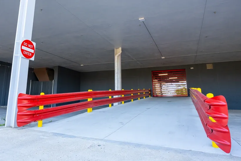 Covered drive-through loading area with protective barriers for indoor storage access