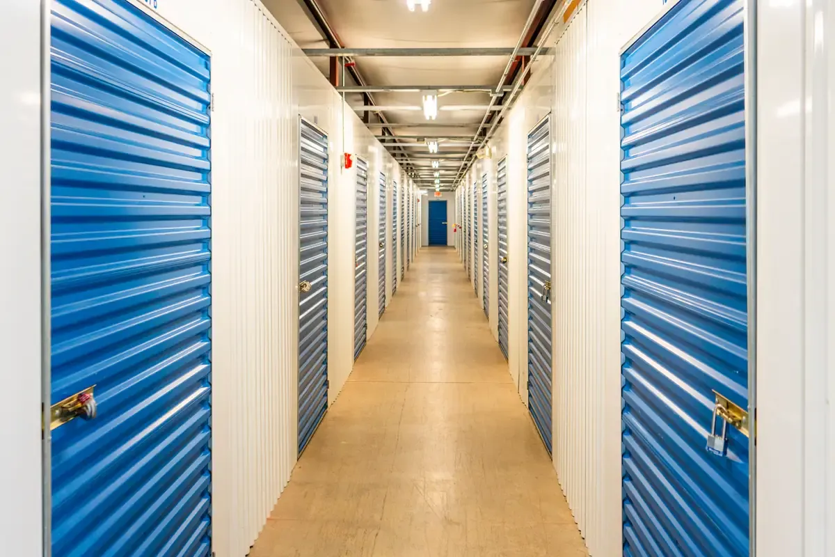Indoor climate-controlled storage hallway with blue roll-up unit doors at Devon Self Storage