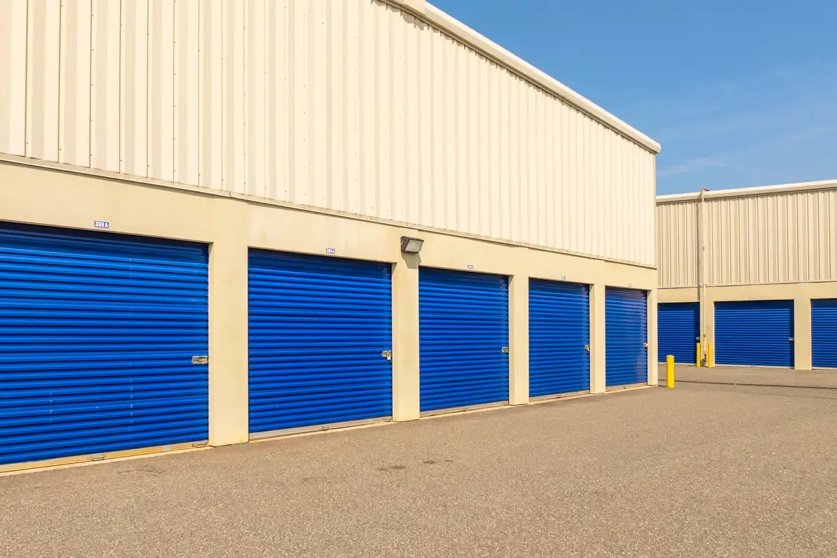 Row of drive-up storage units with blue roll-up doors and wide access lane at Devon Self Storage