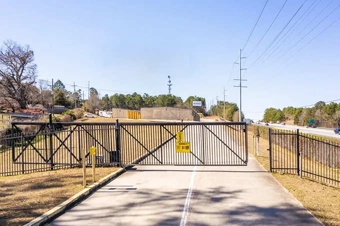 Secure gated entry to storage facility with keypad access and perimeter fencing