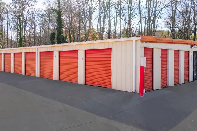 Drive-up storage units with red roll-up doors and paved access