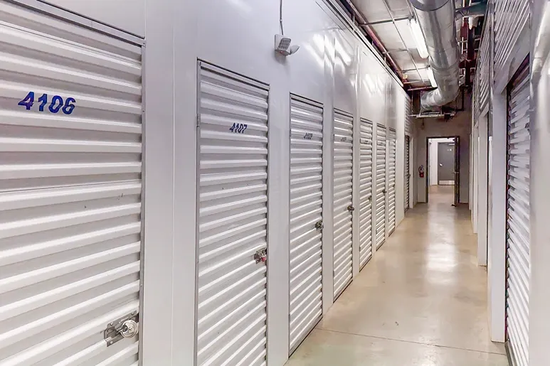 Climate-controlled storage hallway with white roll-up doors and numbered units in indoor facility