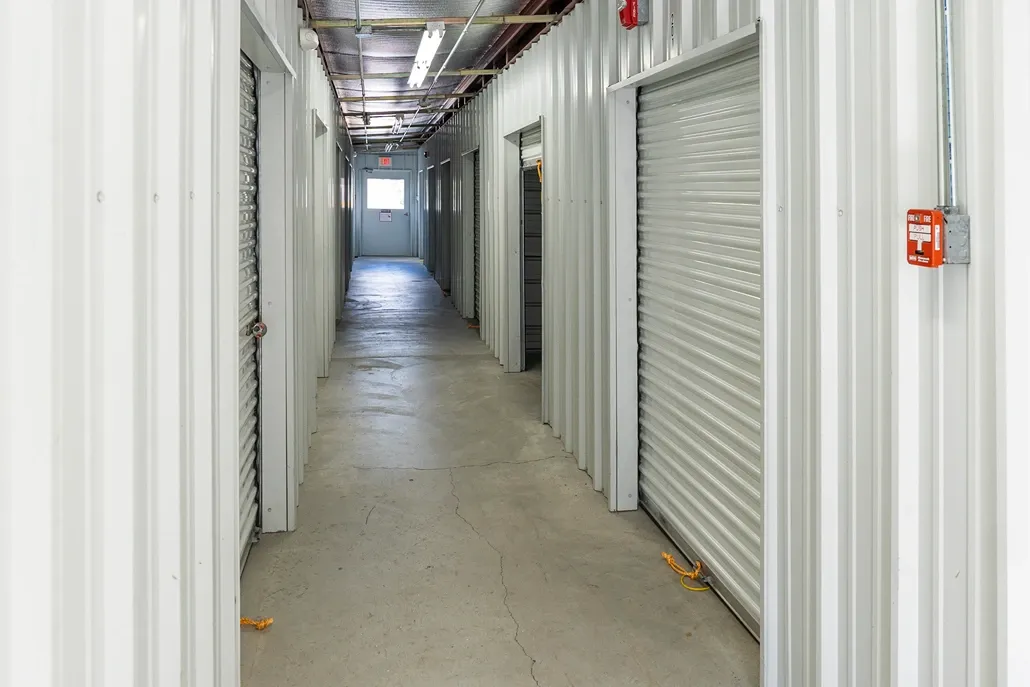 Hallway to indoor storage units. White doors, clean facility. Devon Self Storage Lowell, MA