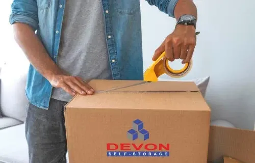 Man taping a Devon Self Storage moving box.