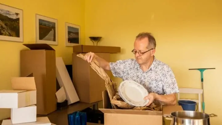 Man unpacking plates from a storage box.