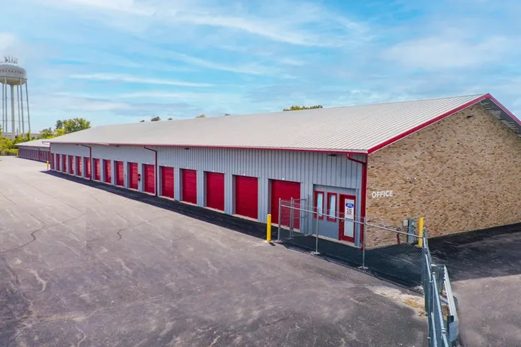 Drive-up self storage units with red roll-up doors and on-site office entrance
