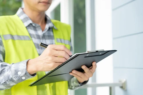 An appraiser surveys a property with a clipboard in hand.