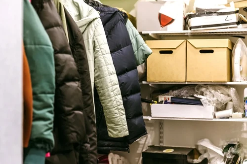 A cluttered closet with coats, boxes, and miscellaneous items that could benefit from closet storage.