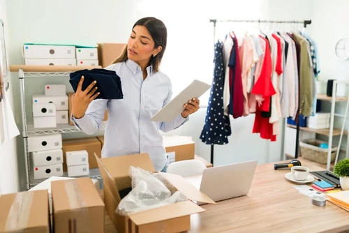 A woman manages her small business from her cluttered home office.