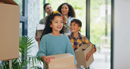 Family carrying boxes into a new home