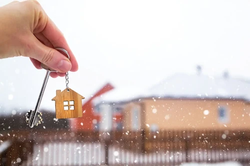 A person holds the key to their new home in the middle of a snowy winter day.