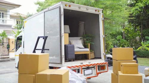 A moving truck being unloaded with boxes.