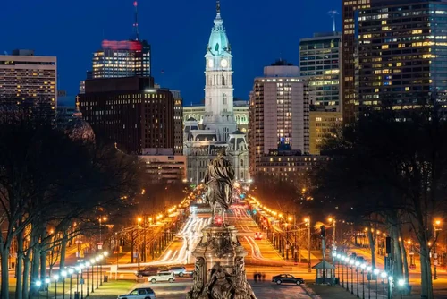 George Washington Statue in front of the lighted Philadelphia skyline at night.