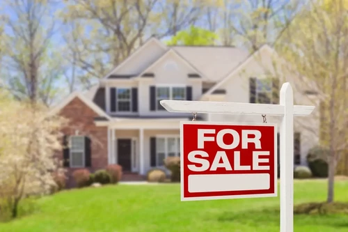 beautiful home with a “for sale” sign in the front yard.