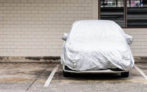 Silver cover for new car which parked in the outdoor ground.