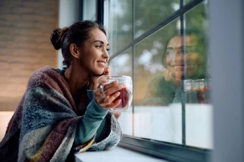 A woman sipping her coffee, looking out the window.