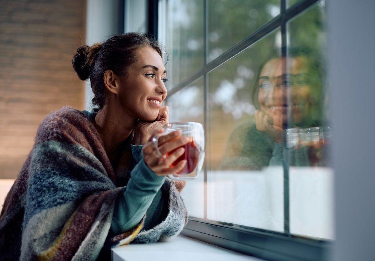 A woman sipping her coffee, looking out the window.