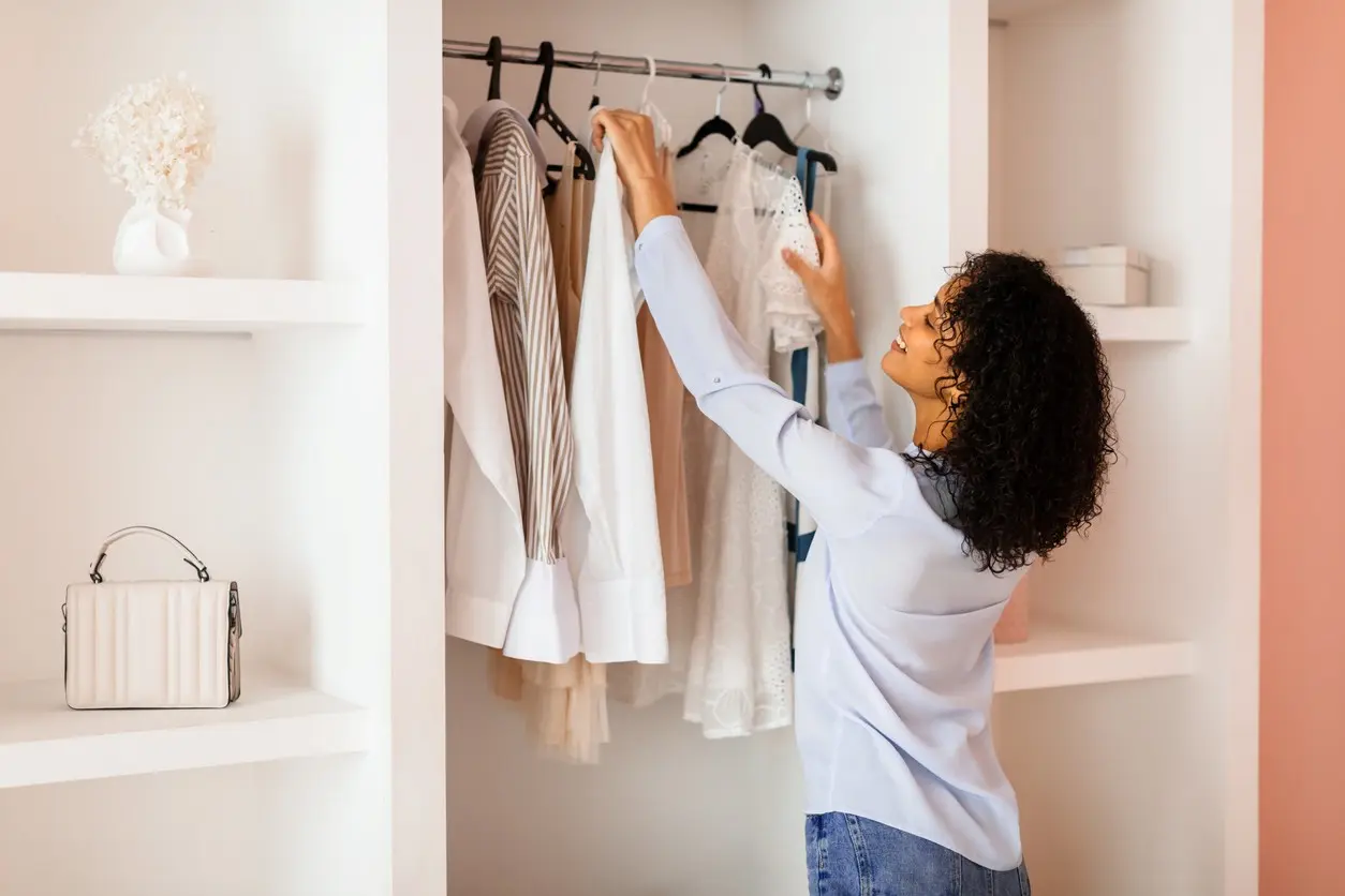 A woman, sorting through her clothes in her closet.