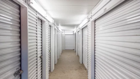 Hallway of storage units, grey walls and doors, concrete flooring. Self Storage Units in Conroe, TX, on Gladstell Road