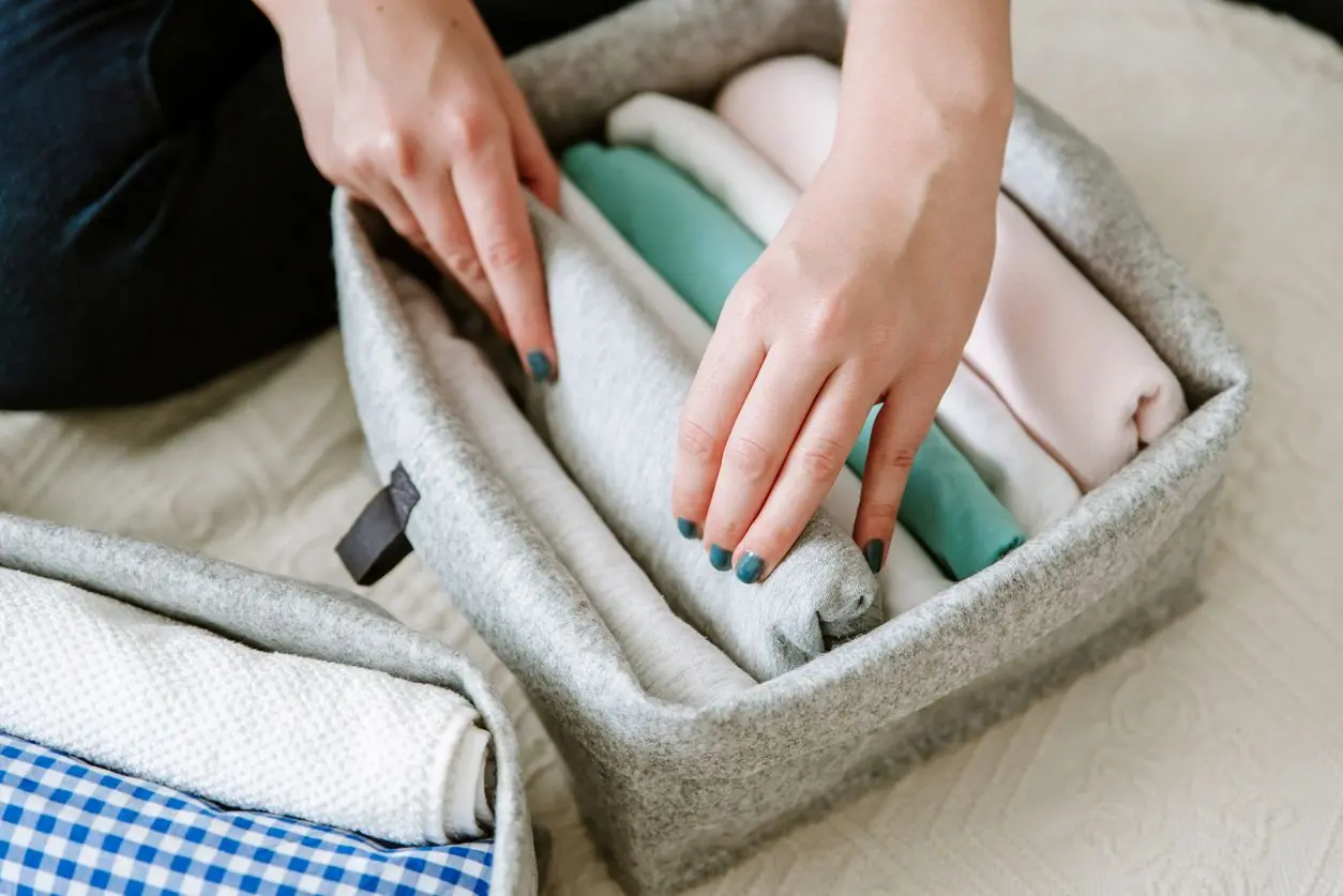 A women folding and putting away clothes in storage.