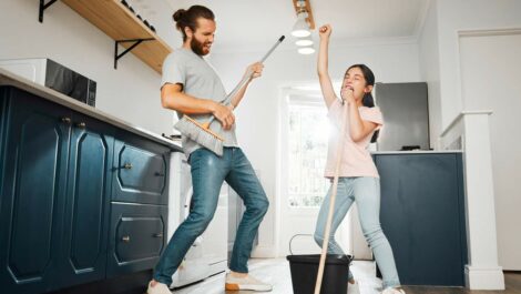 A father and daughter cleaning and using their mops as instruments