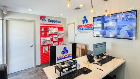 Office area with security tv on wall and wall of moving, packing and storage supplies at Devon Self Storage - Loop 410 in San Antonio, TX
