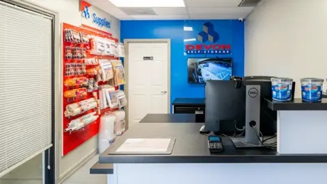 Storage facility office area with security tv on the wall and packing supplies for sale at Devon Self Storage - Peachtree Corners
