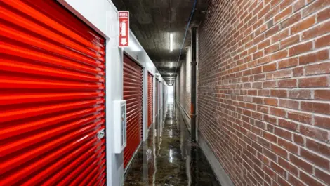 Indoor storage facility with brick hallway and red storage locker doors