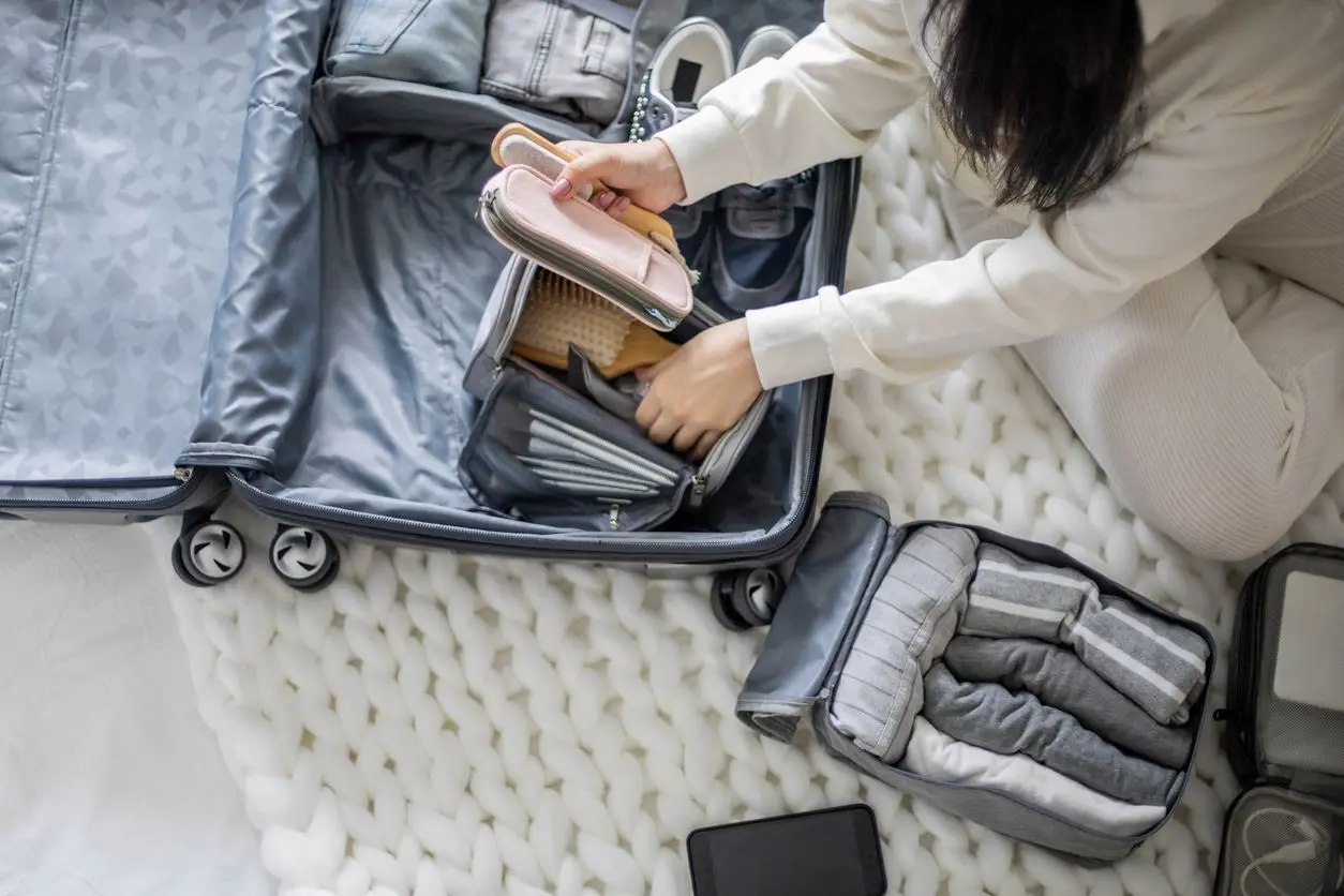 A woman arranges her belongings in packing cubes inside a suitcase.
