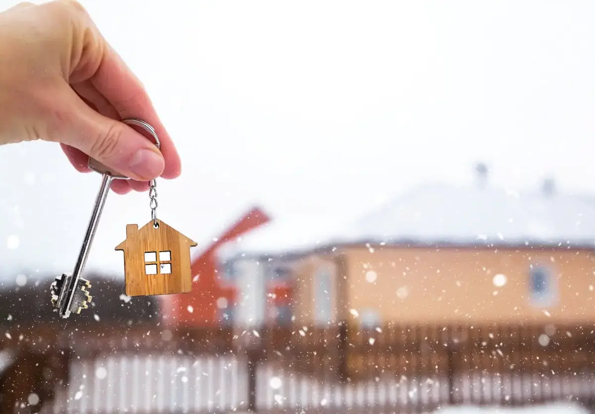 A person holds the key to their new home in the middle of a snowy winter day.