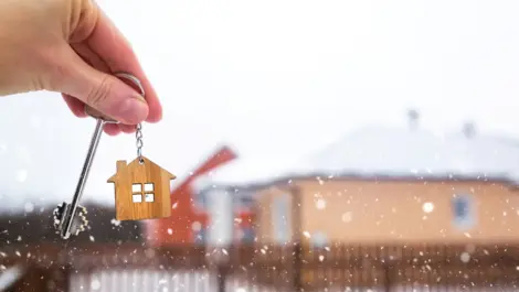 A person holds the key to their new home in the middle of a snowy winter day.
