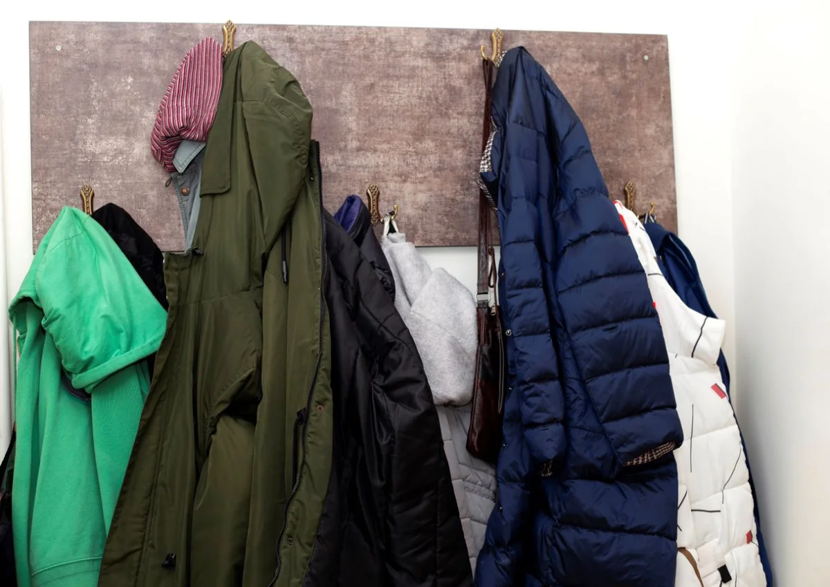 Winter clothing hanging on hooks in a closet.