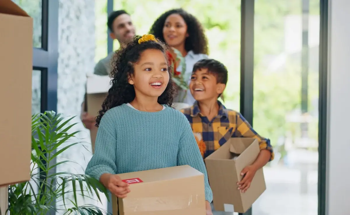 Family carrying boxes into a new home