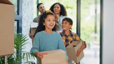 Family carrying boxes into a new home