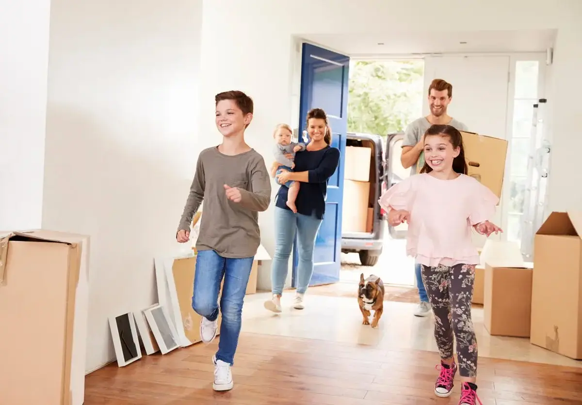 A happy family with a dog runs into their new home while moving.