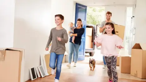 A happy family with a dog runs into their new home while moving.