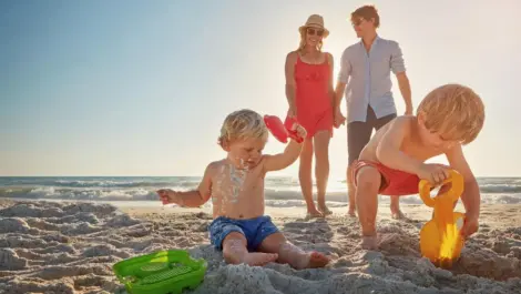 Parents watch their kids play in the sand on a beach vacation.