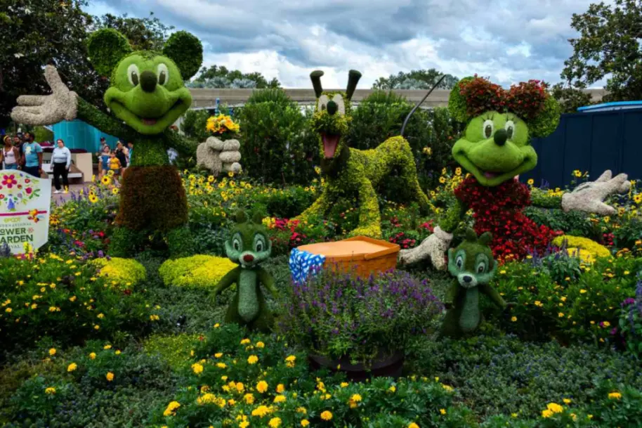 Hedge sculptures of Mickey, Minnie, and Pluto at Epcot, surrounded by flowers.