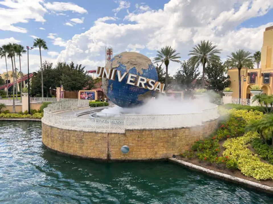 The famous fountain sign at Universal Studios in Florida, with plants and palm trees surrounding it.