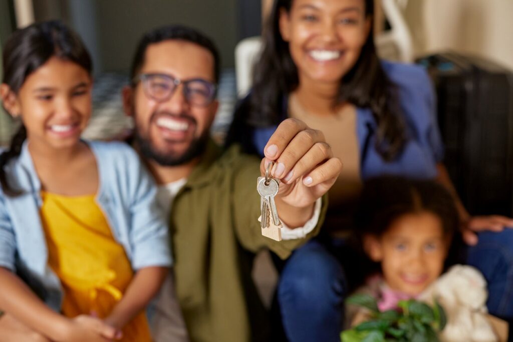 A happy family smiles and holds the keys to their new house. 