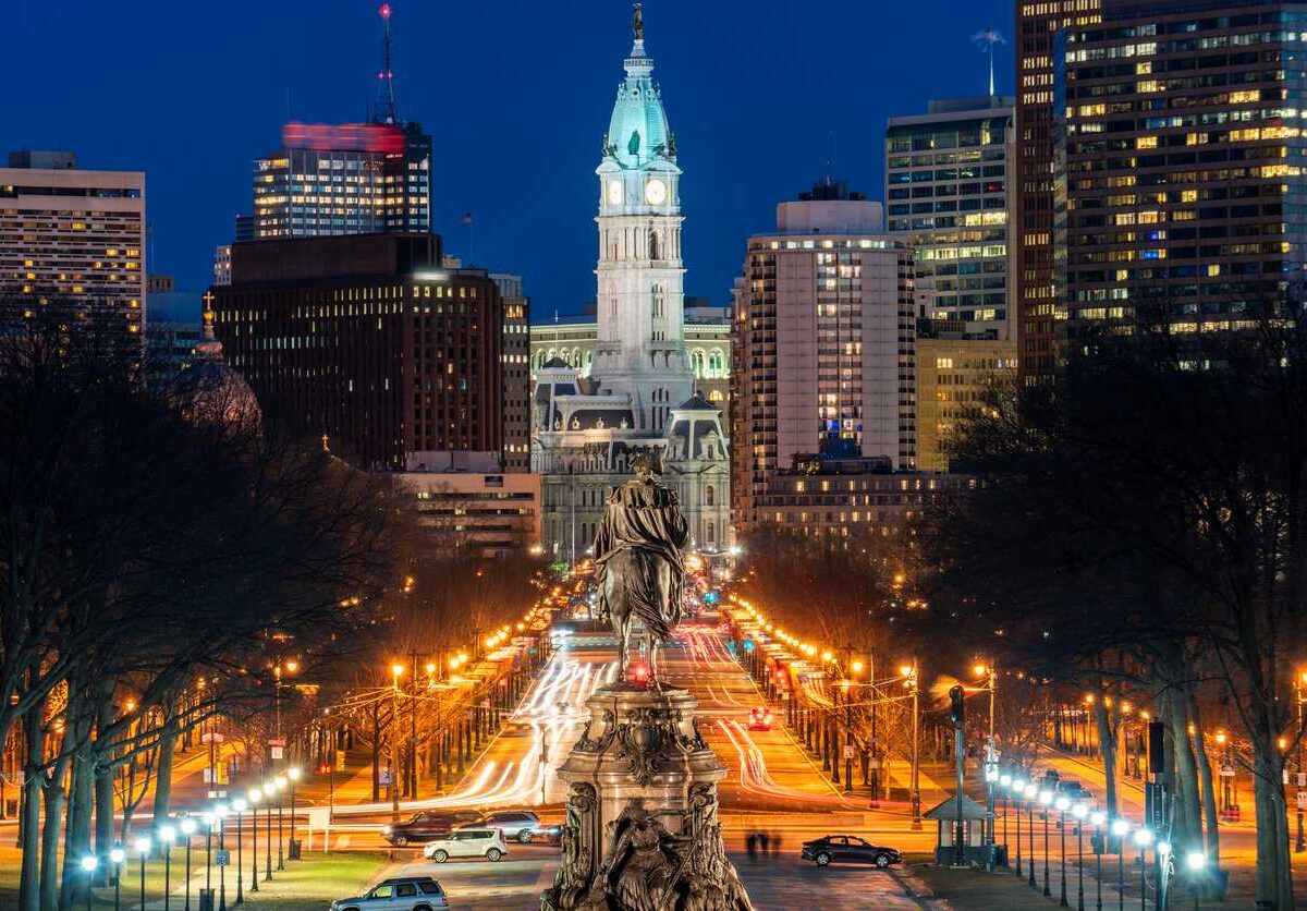 George Washington Statue in front of the lighted Philadelphia skyline at night.