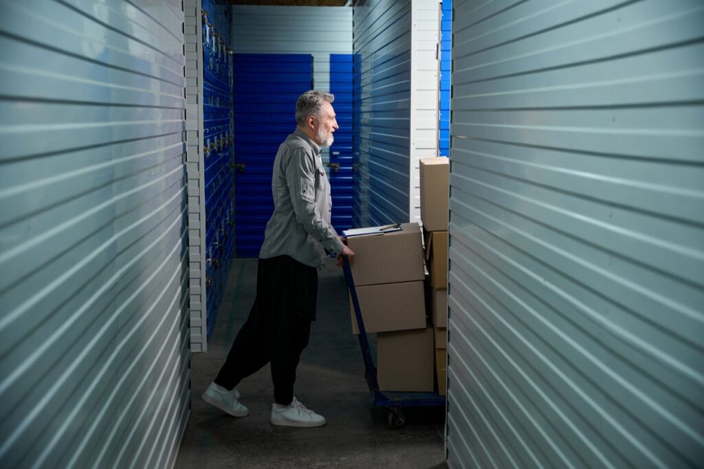 A man pushes a moving cart full of packed cardboard boxes into climate-controlled storage.