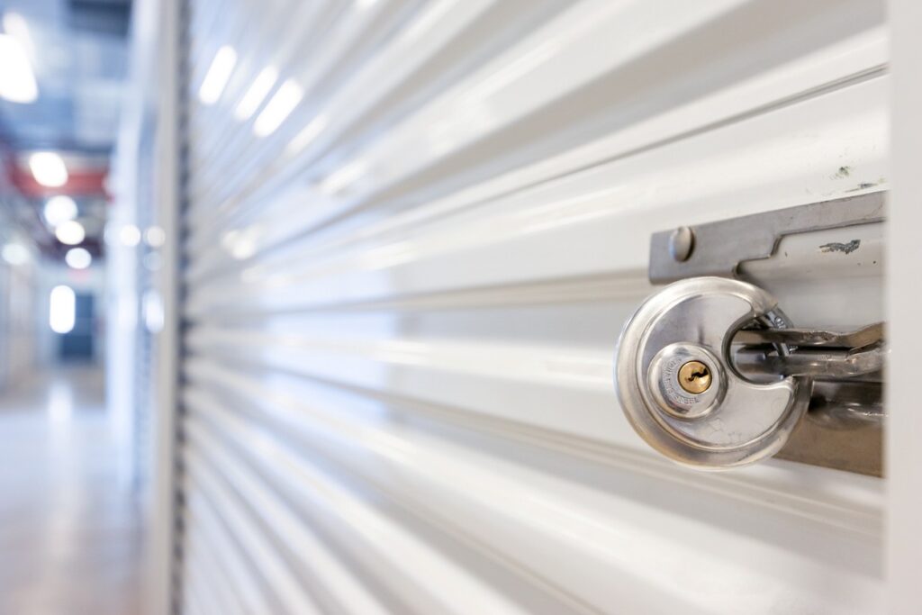 A secure indoor storage unit with a disc lock on a white metal door inside a storage facility. 